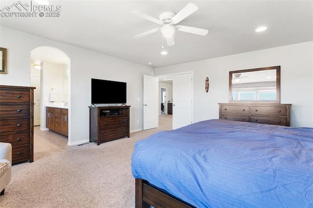 bedroom with ensuite bath, ceiling fan, and light colored carpet