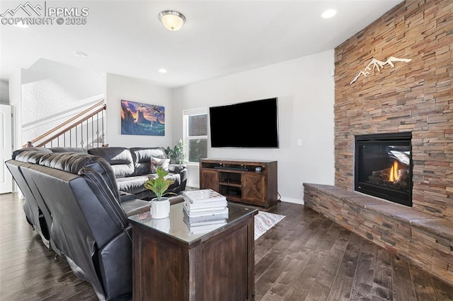 living room featuring a stone fireplace and dark hardwood / wood-style flooring