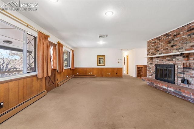 unfurnished living room with wood walls, a fireplace, light colored carpet, and a baseboard heating unit