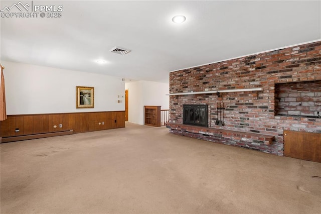 unfurnished living room featuring carpet flooring, a fireplace, baseboard heating, and wooden walls