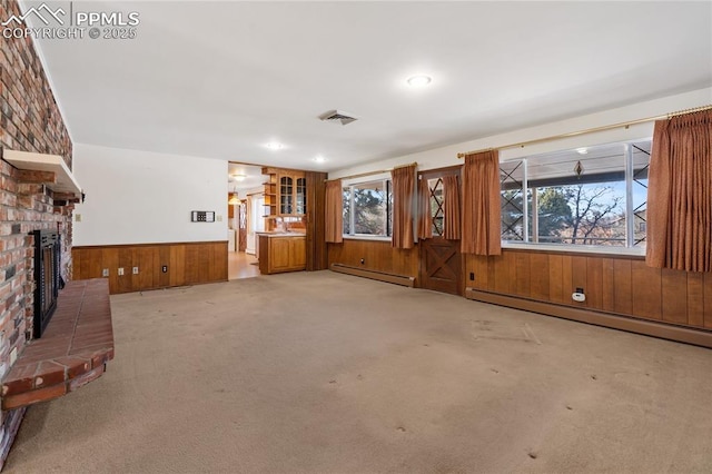 unfurnished living room featuring carpet, a brick fireplace, a wealth of natural light, and a baseboard heating unit