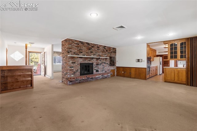 unfurnished living room featuring wooden walls, a fireplace, and light colored carpet