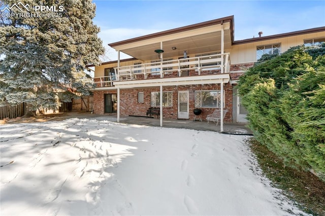 snow covered house with a patio and a balcony