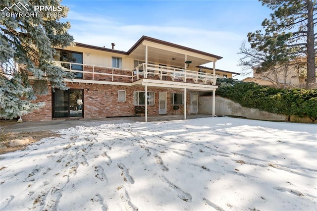 snow covered back of property with a balcony