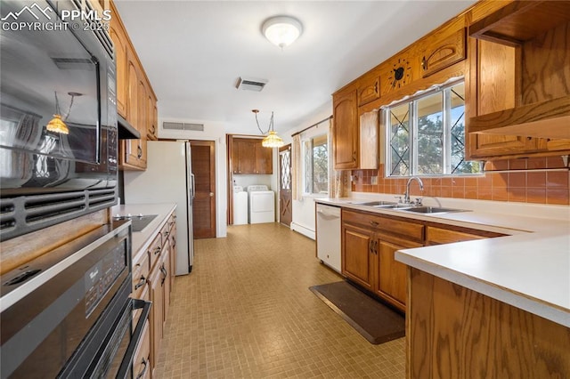 kitchen featuring sink, decorative light fixtures, white appliances, decorative backsplash, and washer and dryer