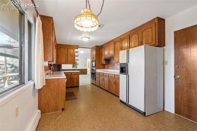 kitchen with a wealth of natural light, white fridge with ice dispenser, decorative light fixtures, and sink