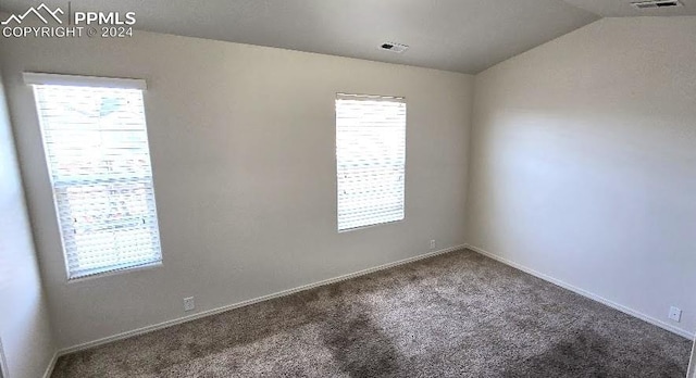 carpeted empty room featuring plenty of natural light and vaulted ceiling