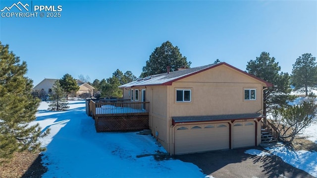 view of snowy exterior with a garage and a deck