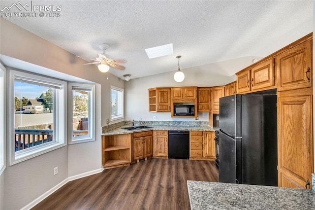 kitchen featuring dark hardwood / wood-style floors, vaulted ceiling with skylight, sink, hanging light fixtures, and black appliances