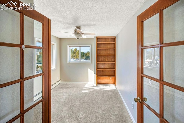 carpeted spare room featuring french doors, ceiling fan, a textured ceiling, and a baseboard heating unit