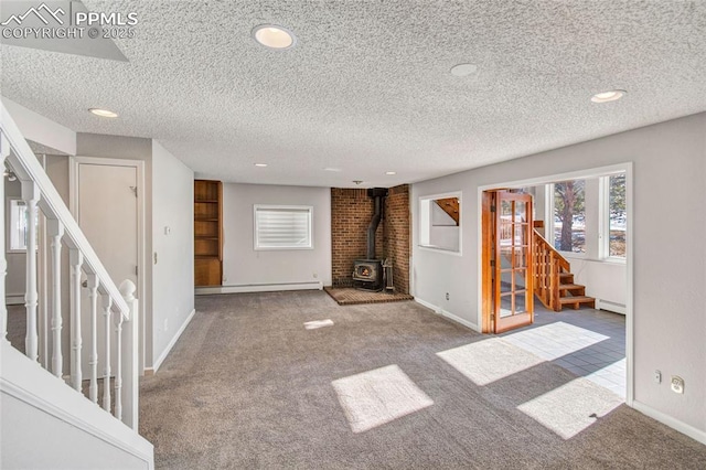 unfurnished living room featuring a baseboard radiator, carpet floors, and a wood stove