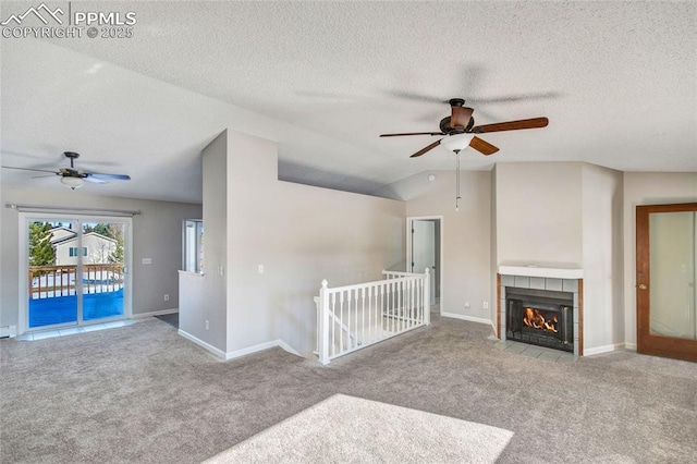 unfurnished living room with light colored carpet, lofted ceiling, a tile fireplace, and a textured ceiling