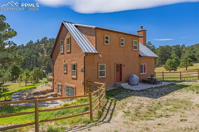 rear view of property with a rural view and a patio area