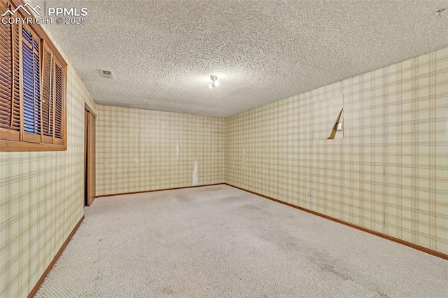 carpeted empty room with a textured ceiling