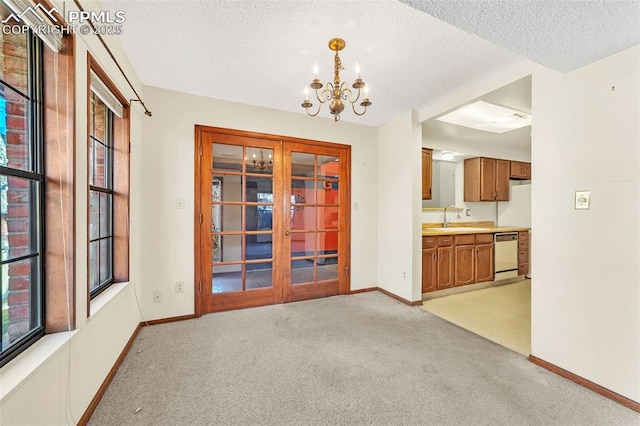 interior space featuring french doors, sink, a textured ceiling, a notable chandelier, and light colored carpet