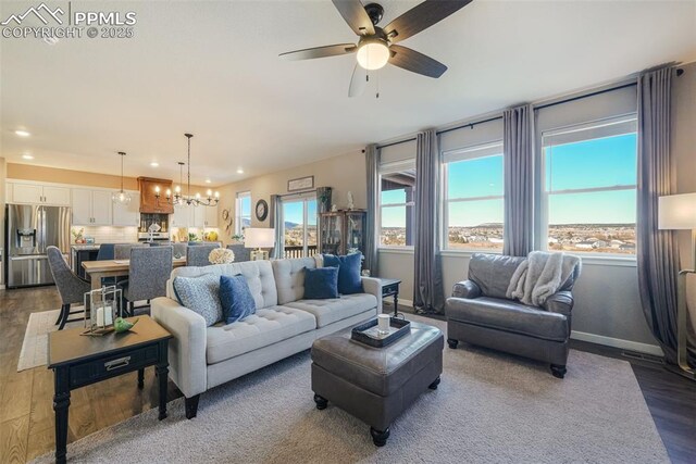 living room with ceiling fan with notable chandelier and hardwood / wood-style flooring