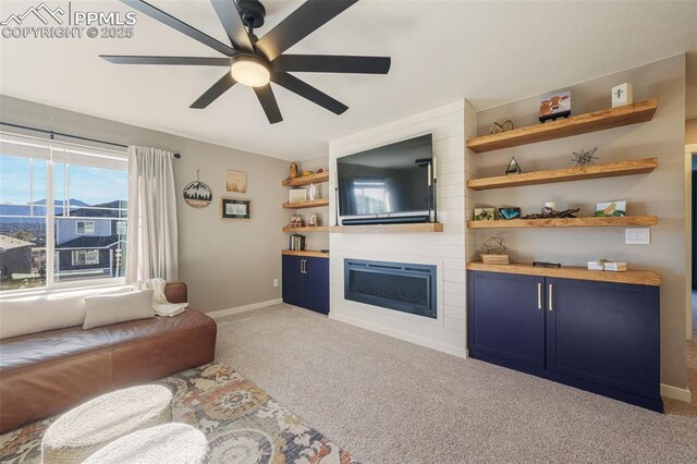 carpeted living room featuring ceiling fan and a large fireplace