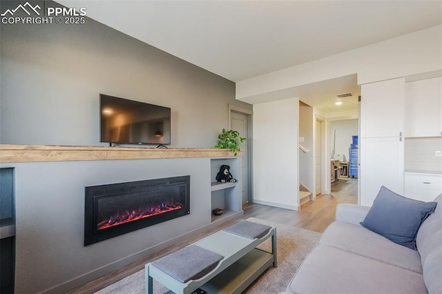 living room featuring built in shelves and light hardwood / wood-style flooring