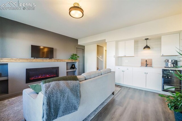 living room featuring wood-type flooring, wine cooler, and sink