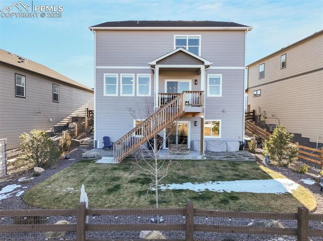 back of house with a patio and a lawn