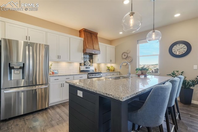 kitchen with white cabinets, appliances with stainless steel finishes, a kitchen island with sink, and sink