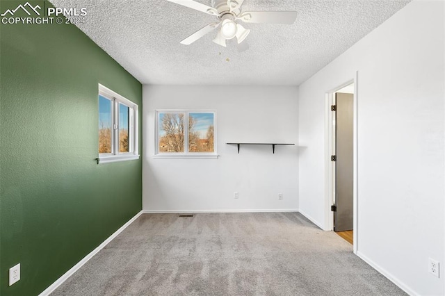 unfurnished room with light carpet, ceiling fan, and a textured ceiling