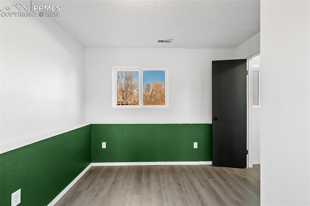 spare room featuring hardwood / wood-style floors and a textured ceiling