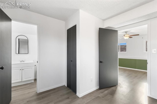 corridor with sink, wood-type flooring, and a textured ceiling