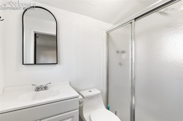 bathroom with an enclosed shower, vanity, and toilet