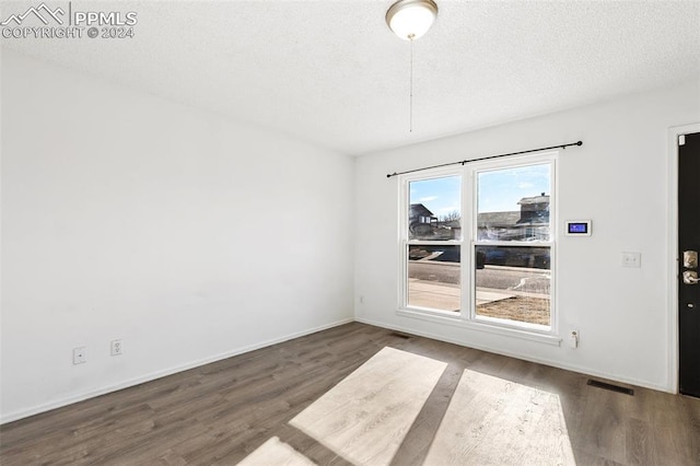 spare room with dark wood-type flooring and a textured ceiling