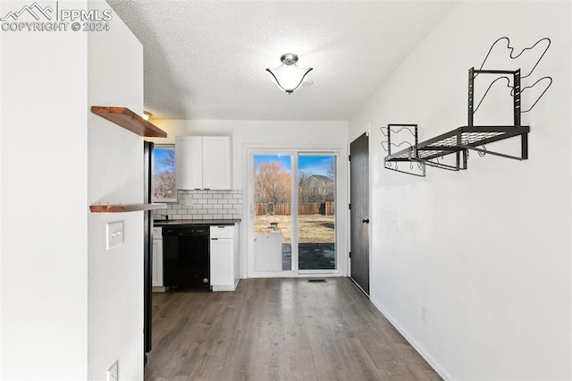 kitchen featuring black dishwasher, backsplash, a textured ceiling, white cabinets, and hardwood / wood-style flooring