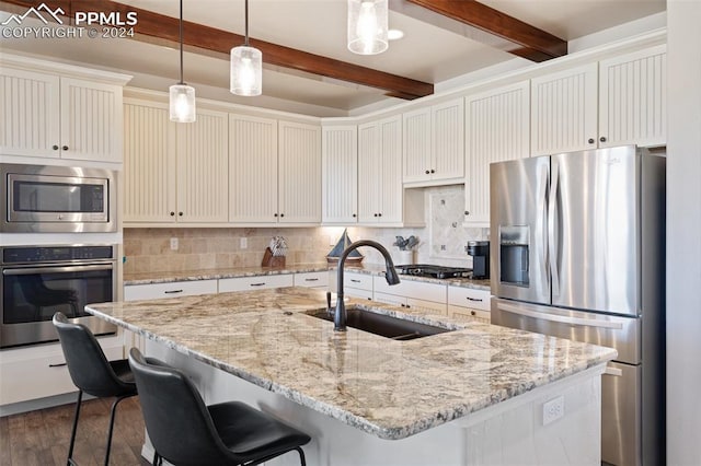 kitchen with dark hardwood / wood-style flooring, stainless steel appliances, sink, beam ceiling, and a center island with sink