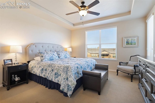 carpeted bedroom with a raised ceiling and ceiling fan