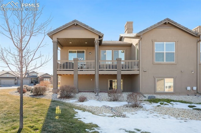 snow covered rear of property with a lawn and a balcony