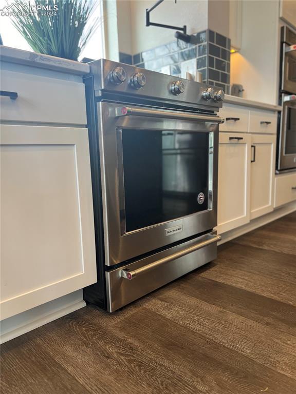 interior details with white cabinets, dark hardwood / wood-style flooring, and stainless steel appliances