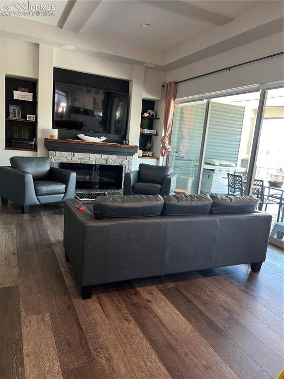 living room with built in shelves, a fireplace, and dark wood-type flooring