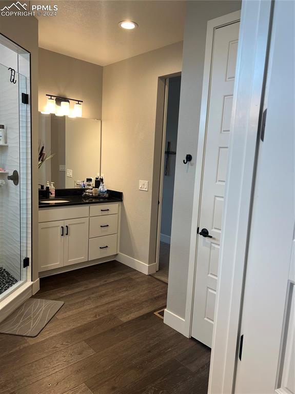 bathroom featuring hardwood / wood-style floors, vanity, and a shower with door