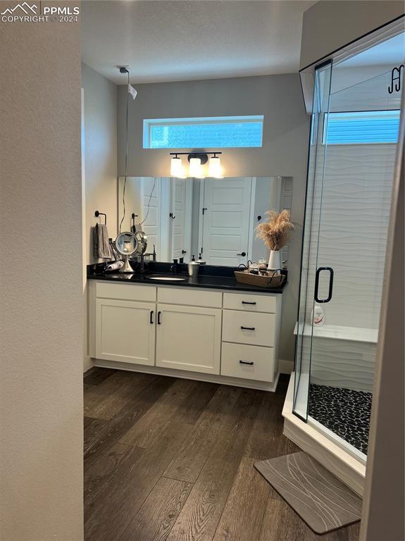 bathroom with hardwood / wood-style floors, vanity, and a shower with door