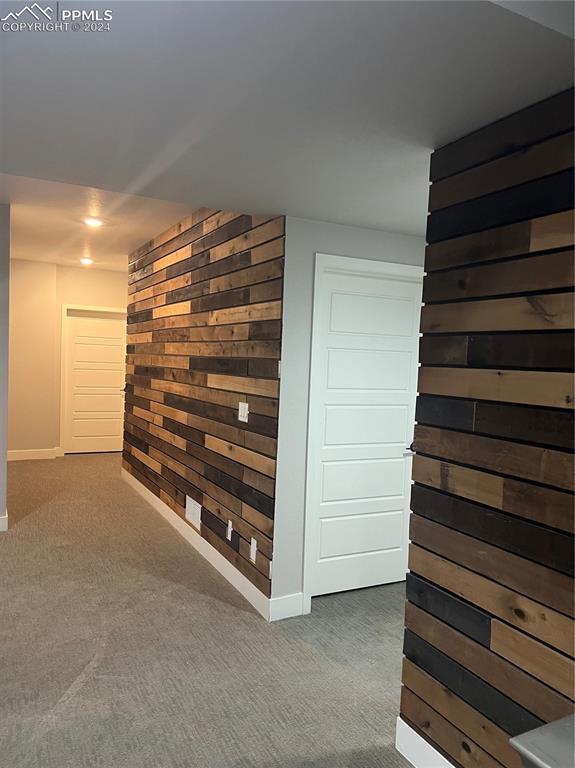 corridor with dark colored carpet and wood walls