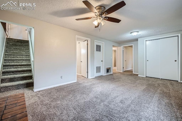 unfurnished bedroom featuring carpet, a textured ceiling, and ceiling fan