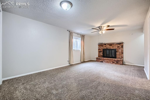 unfurnished living room featuring ceiling fan, carpet floors, a textured ceiling, and a brick fireplace