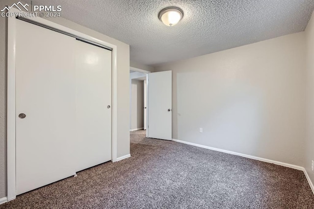 unfurnished bedroom featuring a textured ceiling, carpet floors, and a closet