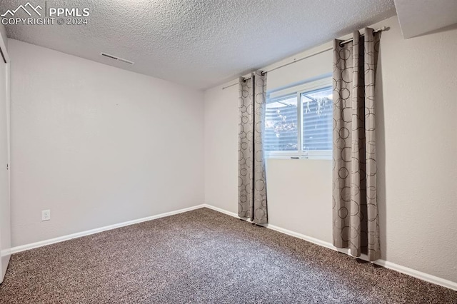 empty room with carpet and a textured ceiling