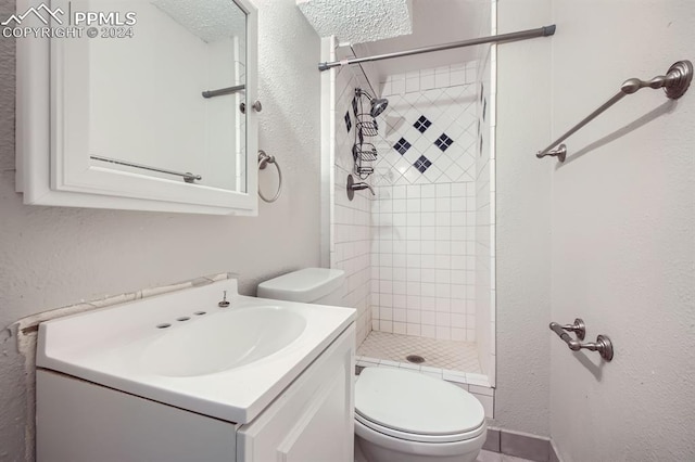 bathroom with vanity, toilet, and tiled shower