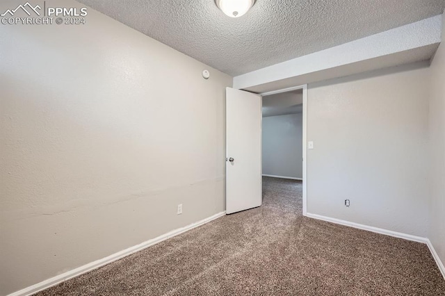 carpeted empty room featuring a textured ceiling