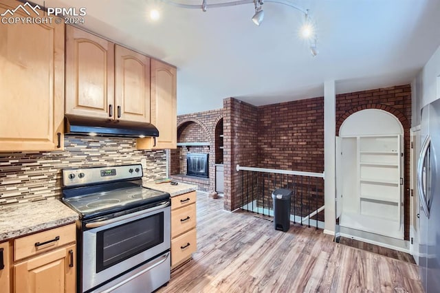 kitchen featuring decorative backsplash, appliances with stainless steel finishes, brick wall, light brown cabinets, and light hardwood / wood-style flooring