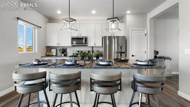 13358 Savannah Falls Ct, Peyton, CO 80831 - kitchen with baseboards, dark wood finished floors, appliances with stainless steel finishes, white cabinetry, and an island with sink