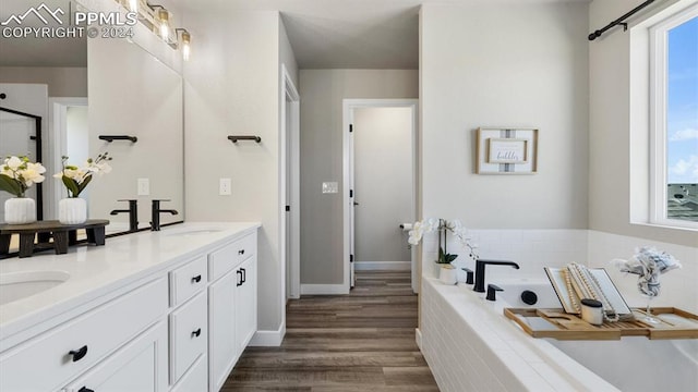 13358 Savannah Falls Ct, Peyton, CO 80831 - full bath featuring baseboards, a sink, a garden tub, double vanity, and wood finished floors