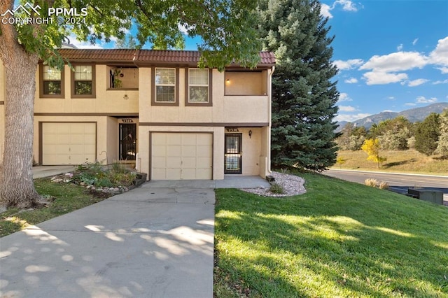 townhome / multi-family property with a mountain view, a garage, and a front lawn