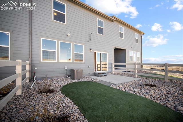 rear view of house with central AC unit, a patio area, and a yard